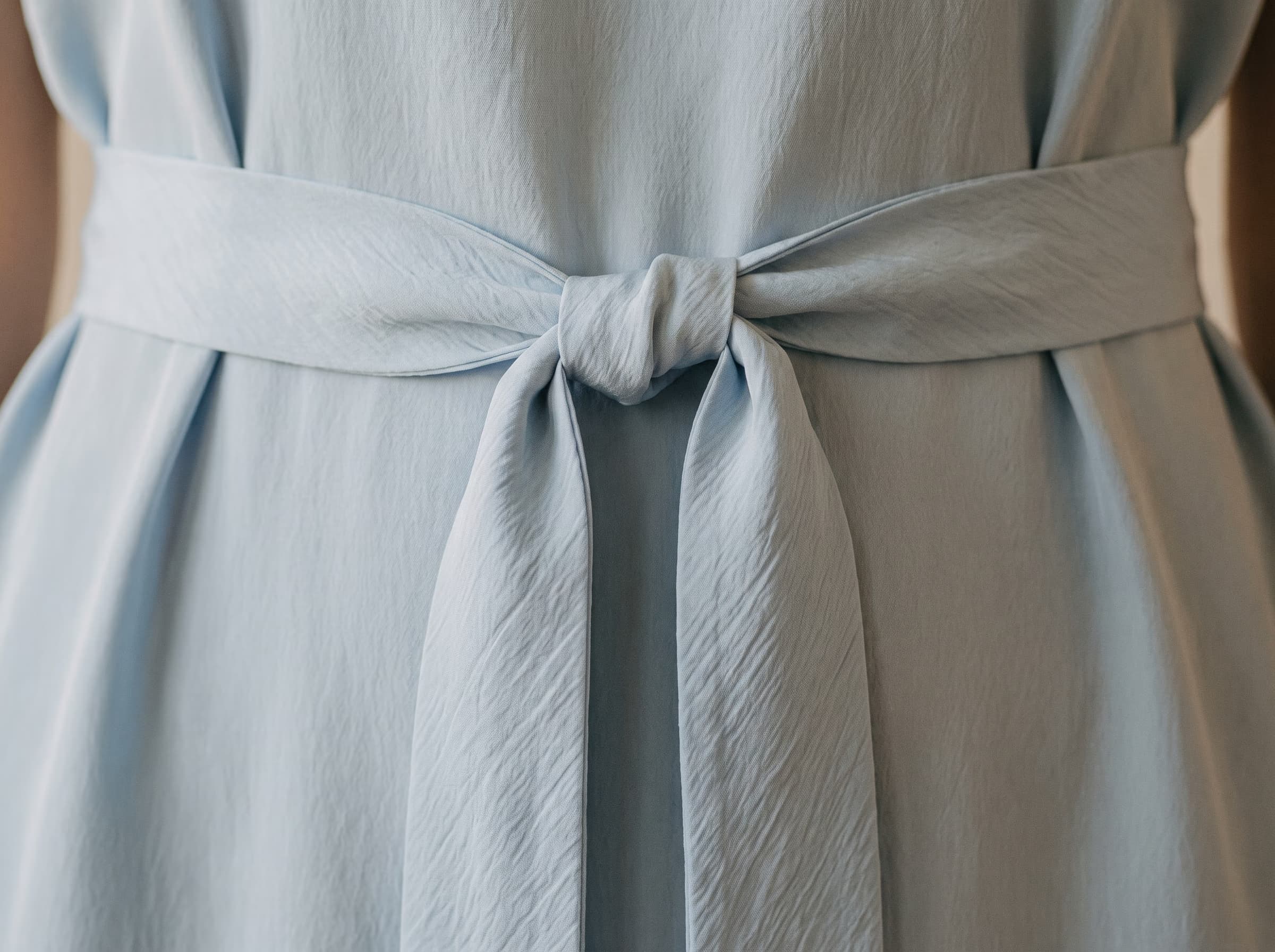 La ceinture de la robe Menara en bleu voile, coupée en biais et nouée à plat.